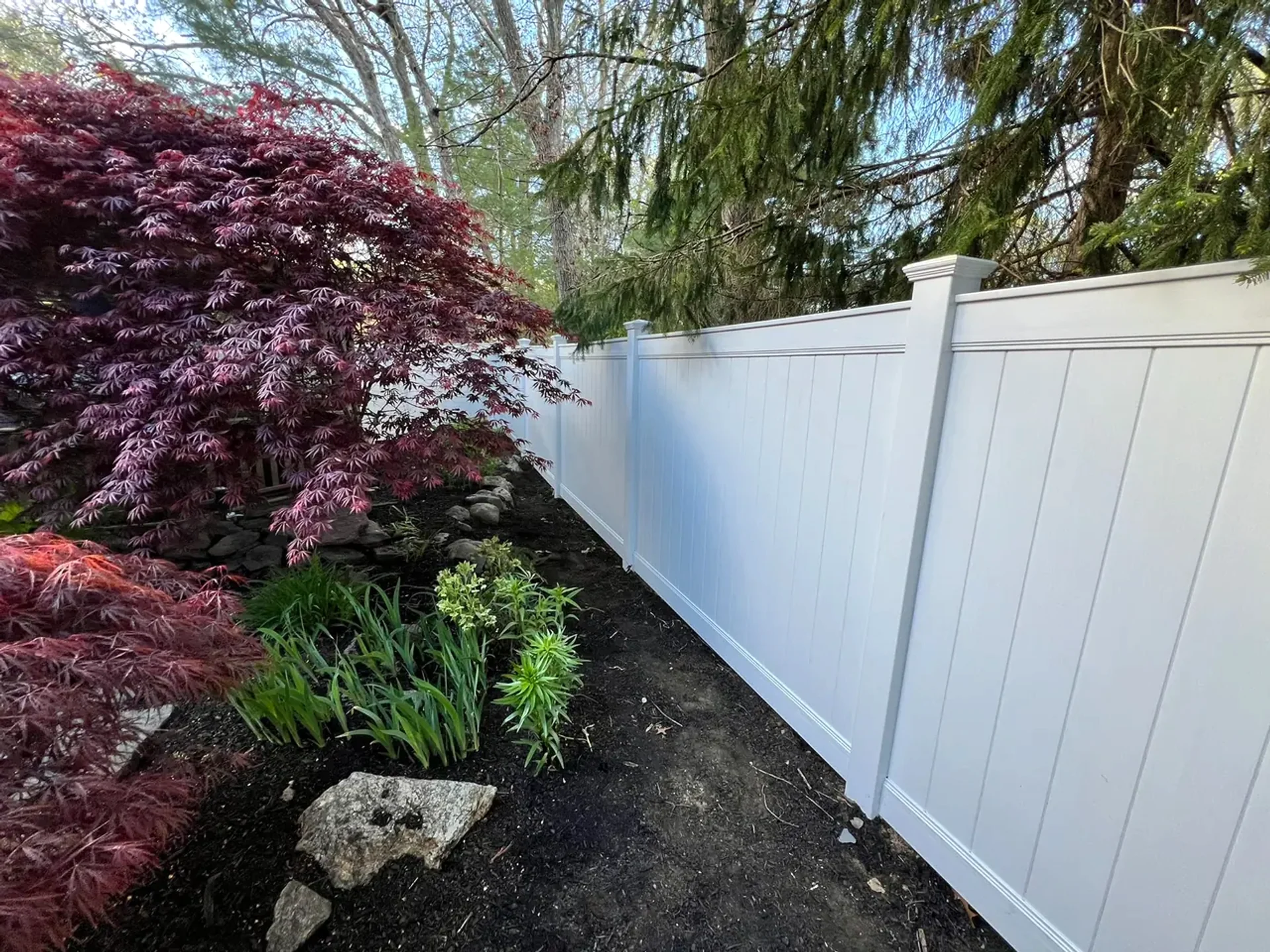 White vinyl fence beside landscaping